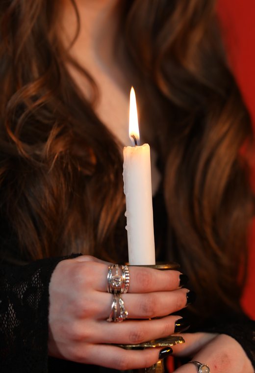 Hand wearing rings holding a lit candle